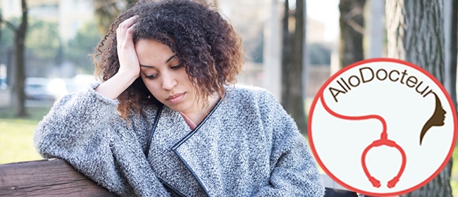 Sad black woman seated alone on a bench at the park