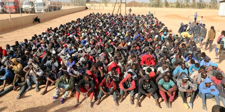 Migrants sit at a detention center in Gharyan